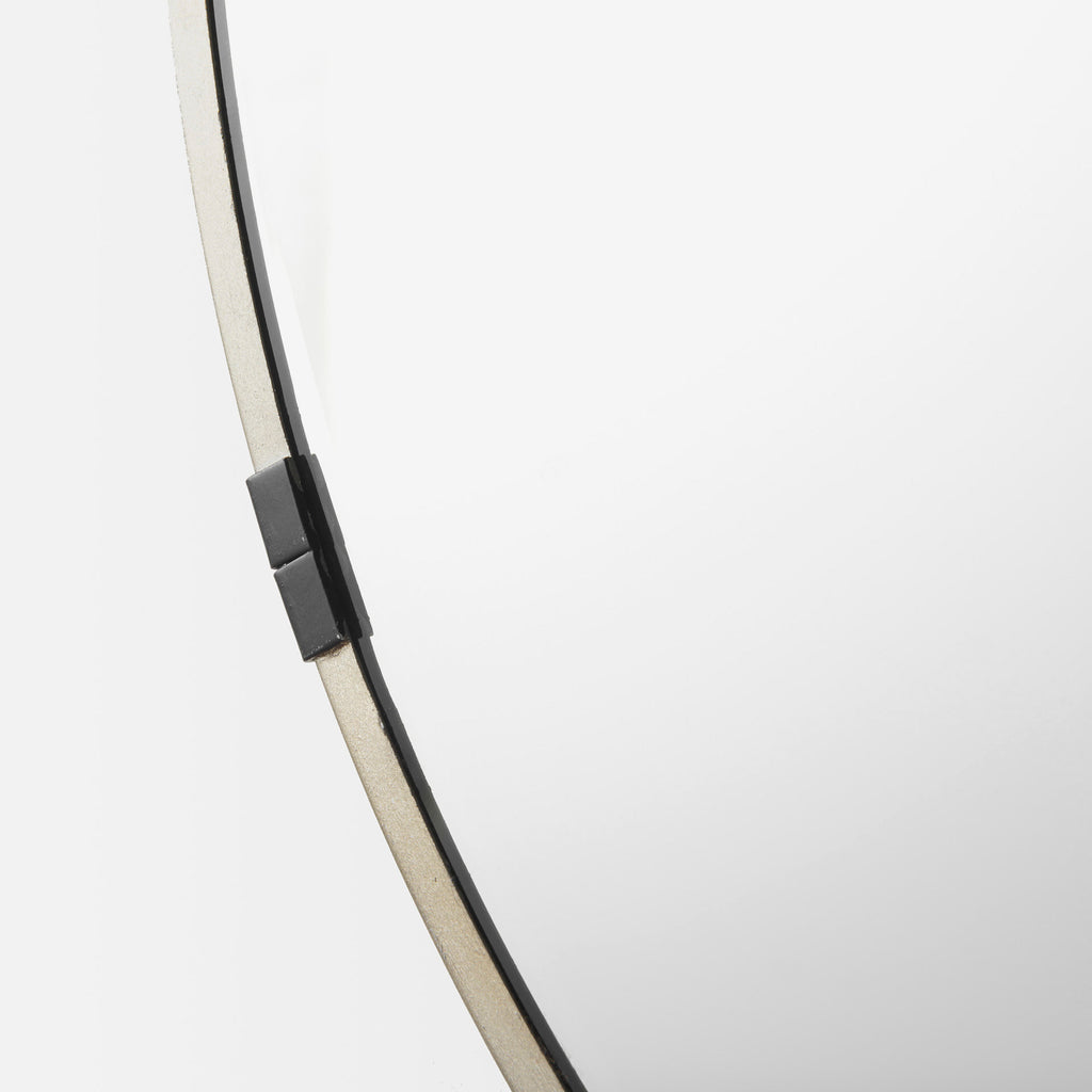 A round mirror with gold finish and black metal accent