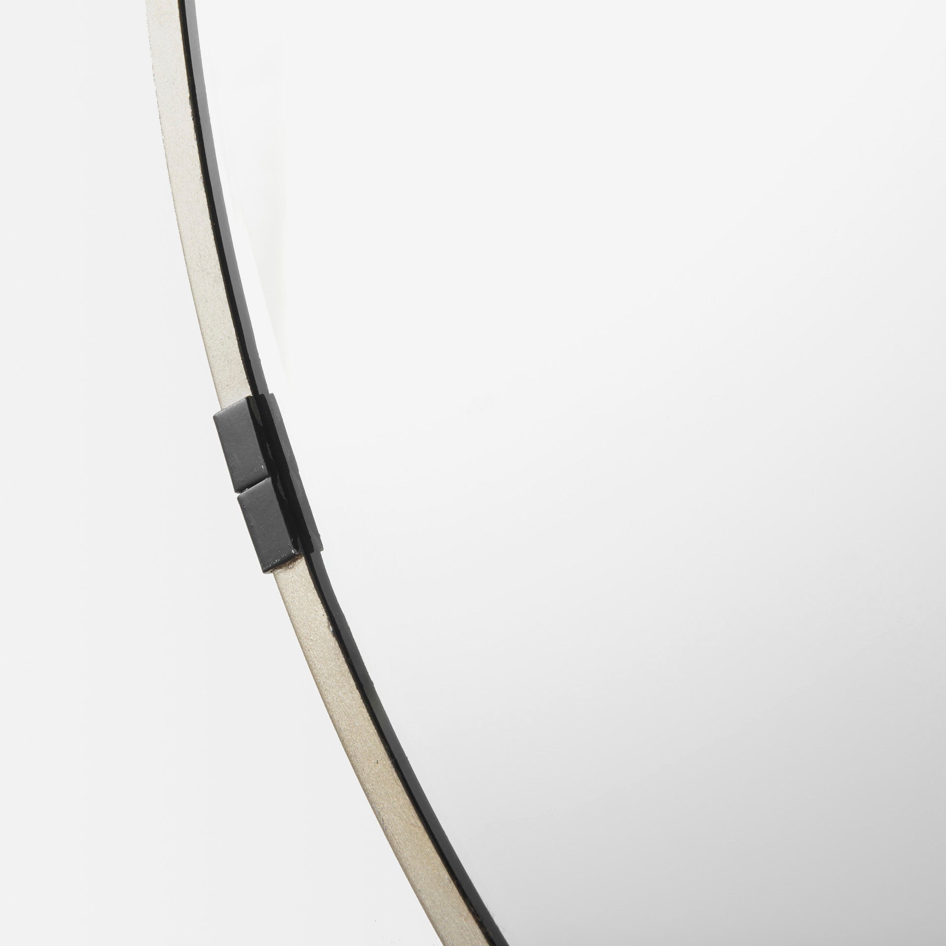 A round mirror with gold finish and black metal accent