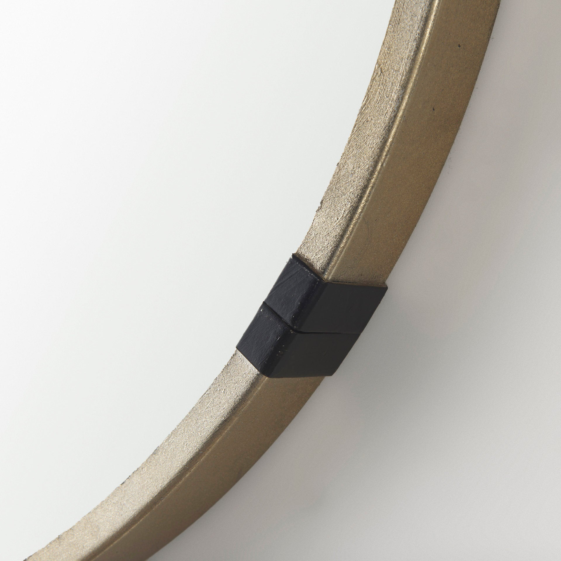 A round mirror with gold finish and black metal accent