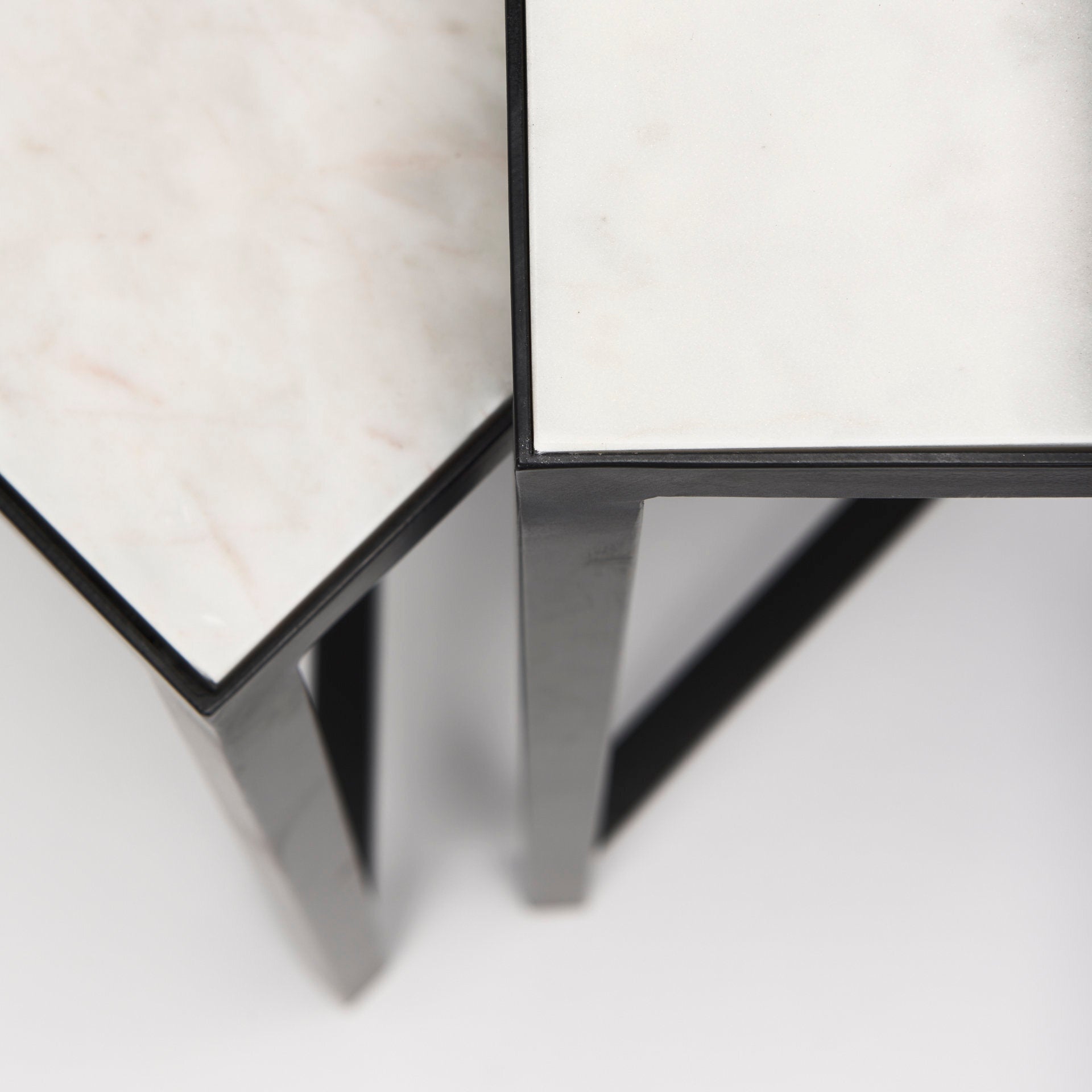This set of nesting tables feature square, marble tops that rest neatly upon crisscross, iron frames.