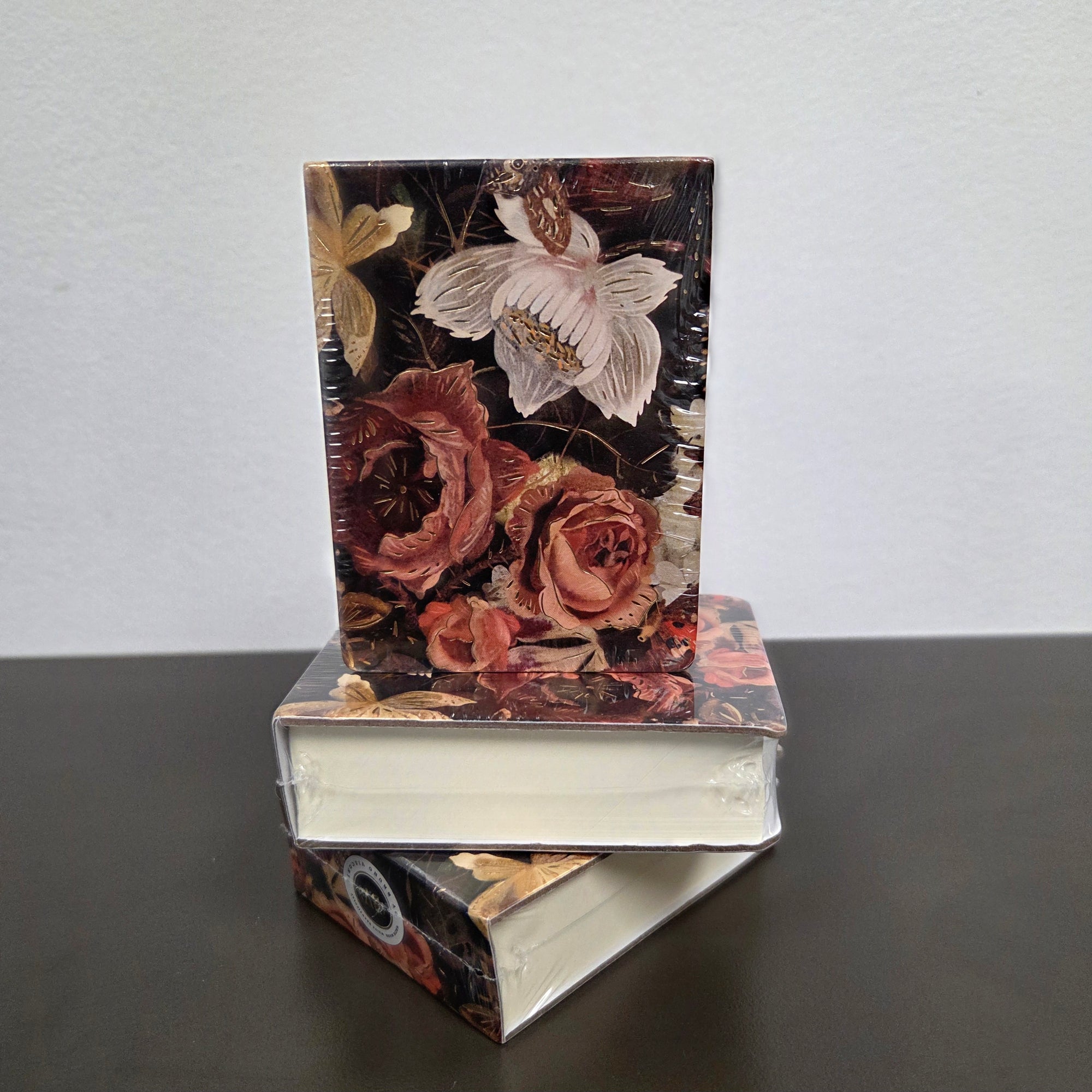 Stack of books with floral design on a dark surface